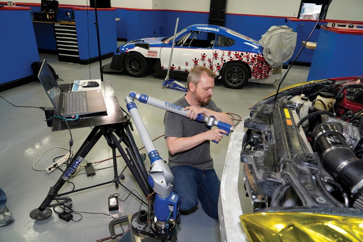 A FaroArm 3D scanner in a machine shop environment, accurately measuring a car part.