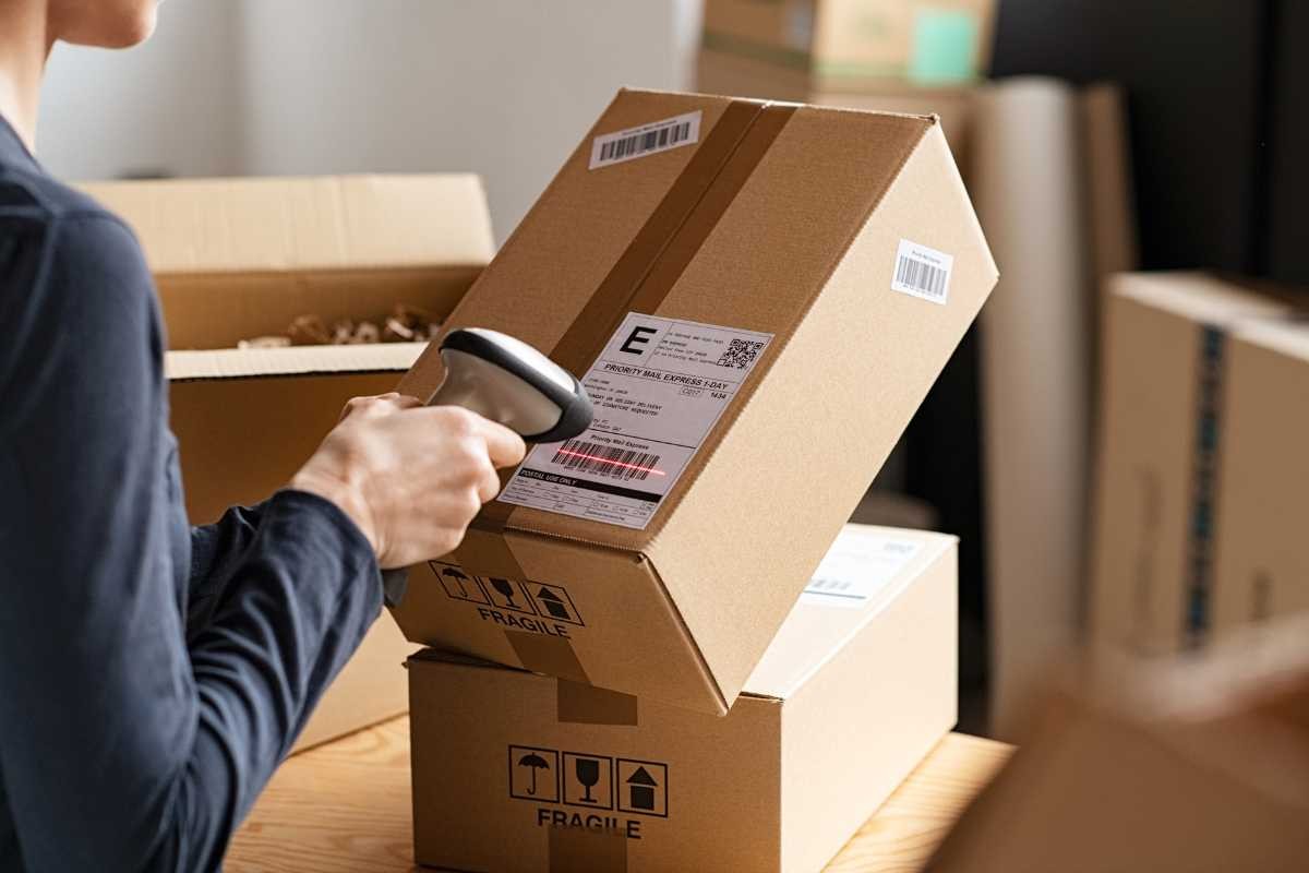 A staff member scans a barcode on a cardboard box, demonstrating barcode price scanning.