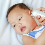 Baby getting temperature checked at urgent care, highlighting the availability of pediatric urgent care services for common illnesses.