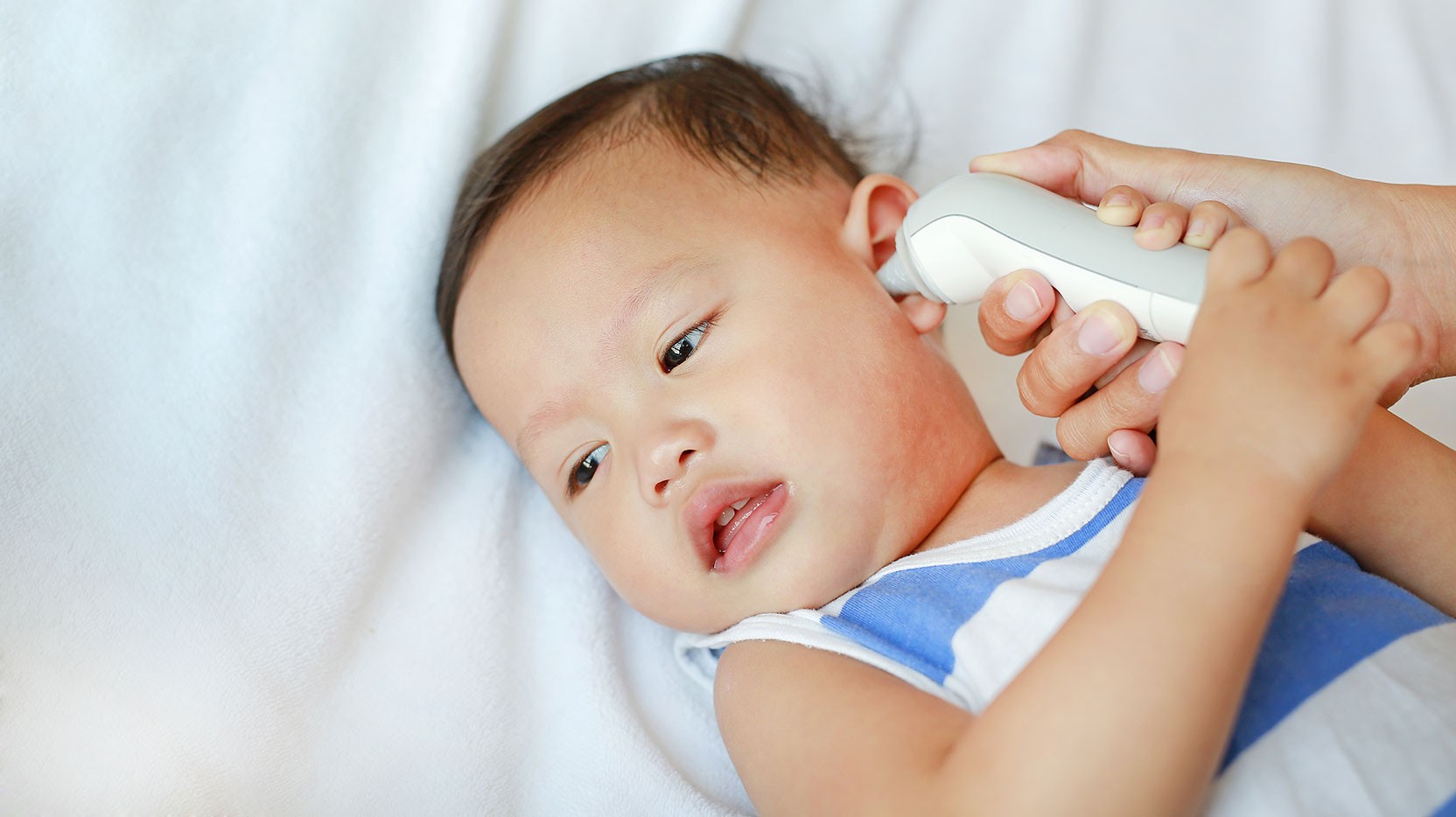 Baby getting temperature checked at urgent care, highlighting the availability of pediatric urgent care services for common illnesses.