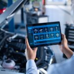 Car Service Manager or Mechanic Uses a Tablet Computer with a Futuristic Interactive Diagnostics Software. Specialist Inspecting the Vehicle in Order to Find Broken Components In the Engine Bay.