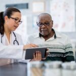 Doctor explaining medication schedule to senior patient using a tablet, highlighting urgent care communication and digital health records.