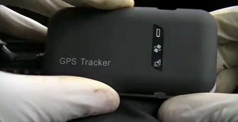 Hands holding a small car GPS tracker device