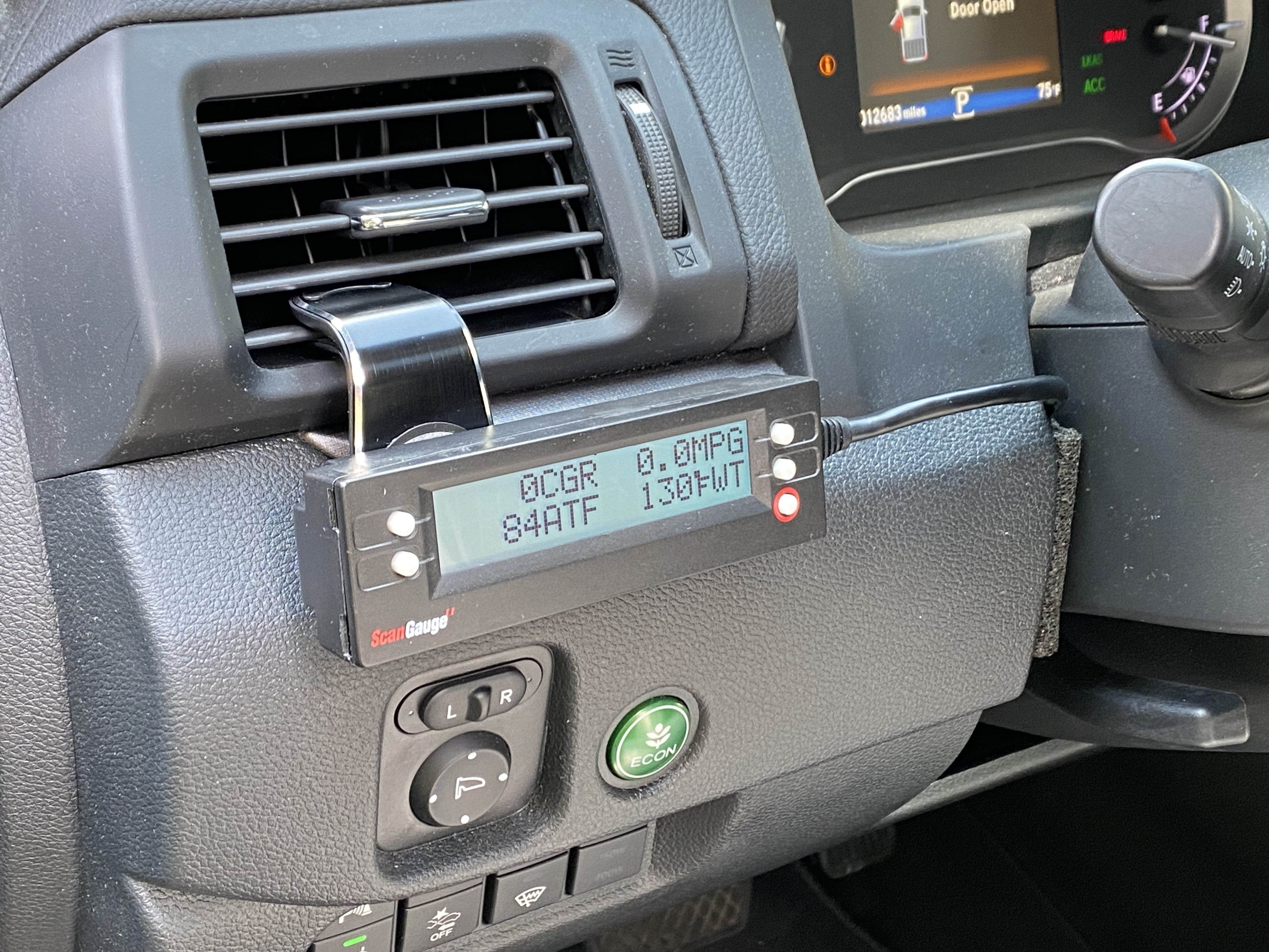 Dashboard view of ScanGauge 2 mounted on air vent magnetic car mount showing steering wheel and car interior