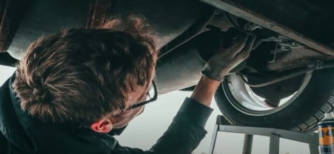 Mechanic searching for GPS tracker in a car interior