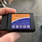 KOBRA OBD2 scanner device, angled view, showcasing its compact design and OBD2 connector.