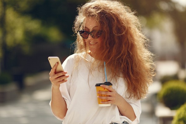 Person holding a Starbucks cup and phone